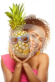 Model with pineapple in hands. African American Girl with Exotic Fruit. Cheerful woman with a smile relaxing on vacation. Image