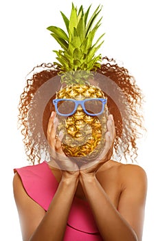 Model with pineapple in hands. African American Girl with Exotic Fruit. Cheerful woman with a smile relaxing on vacation. Image