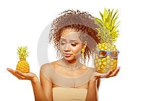 Model with pineapple in hands. African American Girl with Exotic Fruit. Cheerful woman with a smile relaxing on vacation. Image