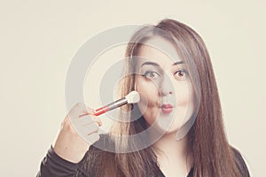 Model plus size with sweet donut, happy smiling girl posing with cosmetic, doing makeup for her self with brush in black bodysuit