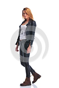 Model pose in leather jacket while walking in studio and looking