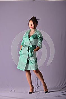 Model posing in light green raincoat standing in the studio. Retro style