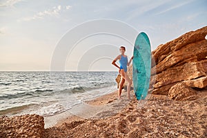 Model posing next to surfboard on nature. Summer holiday on sandy beach, adventure and surf hobby concept. Copy space