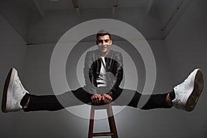 Model posing seated on stool with hands between spread legs