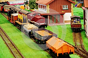 Model railroad system with freight train and nostalgic passenger train at the small train station