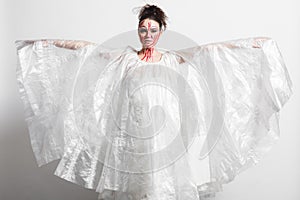 Model in a raincoat made of cellophane and in creative make-up