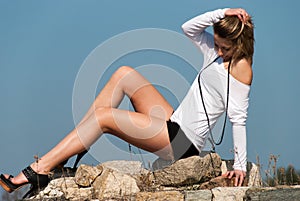 Model reclining on rocks, shows off her long legs