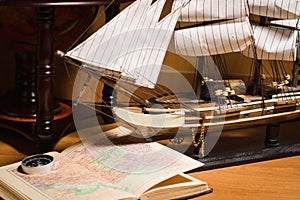 Model sailing ship, map book and compass