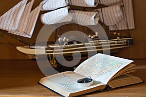 Model sailing ship, map book and compass