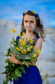 Beautiful cute girl in blue dress with bouquet of yellow
