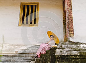 Model sitting outside Ancient shrine Wat Phra Singh in Chiang Mai Thailand