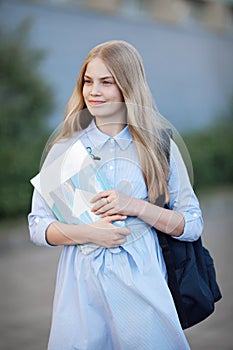 Model student in a blue dress with a backpack, notebooks and textbooks. Education