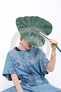 Model in studio. Trendy jeans overalls. Blue denim.  Palm leaf. Street Style. Fashion lookbook concept