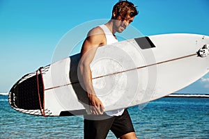 Model surfer wearing casual clothes going with surfboard on blue ocean