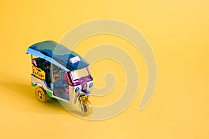 Model Toy tuk tuk isolated on yellow background. Thai traditional taxi in Bangkok Thailand. Souvenir