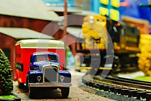 Model Truck and Locomotive on track with vintage box truck in forefront.