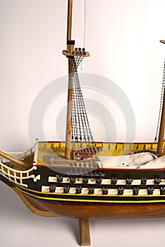 Model of a warship with cannons and sails on a white background.