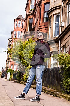 Model wearing blue skinny jeans, black sneakers and sunglasses