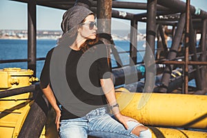 Model wearing plain tshirt and sunglasses posing over street wall photo