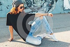 Model wearing plain tshirt and sunglasses posing over street wall photo