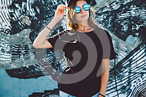 Model wearing plain tshirt and sunglasses posing over street wall photo