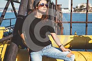 Model wearing plain tshirt and sunglasses posing over street wall photo