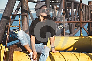 Model wearing plain tshirt and sunglasses posing over street wall