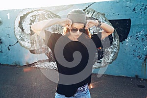 Model wearing plain tshirt and sunglasses posing over street wall