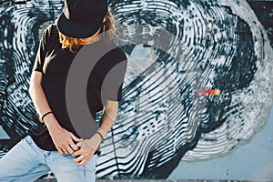 Model wearing plain tshirt and sunglasses posing over street wall