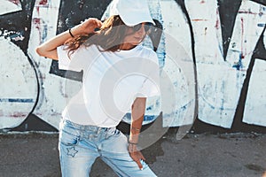 Model wearing plain tshirt and sunglasses posing over street wall