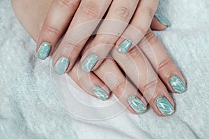 Model woman showing shellac marble green pastel manicure with gold leaf on short nails photo