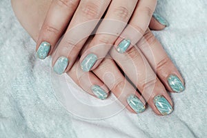 Model woman showing shellac marble green pastel manicure with gold leaf on short nails