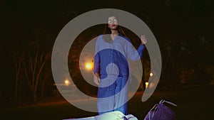 Model woman standing waste bags after cleanup night park under ambient lanterns.