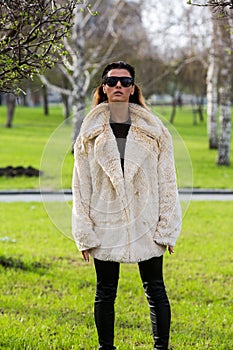 Model woman in sunglasses and fur coats in Park