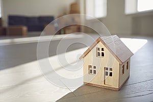 Model of the wooden house on the floor in the new bright sunny house.