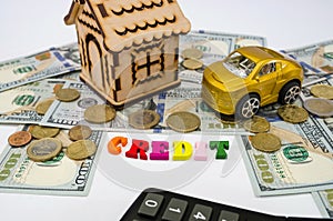 A model of a wooden house with a key, a car, money and the word `credit` from letters. real estate, mortgage and investment concep