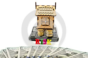Model of a wooden house, money and a calculator on white. The word `risk` from the letters. real estate, mortgage and investment c
