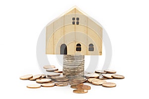 A model wooden house on stack of coins on white background