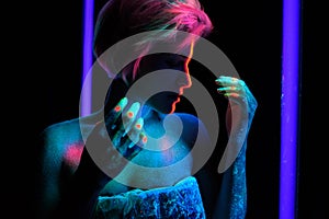 Model young beautiful girl portrait in studio with creative makeup, in neon ultraviolet lamp. Glows in the dark. Hair