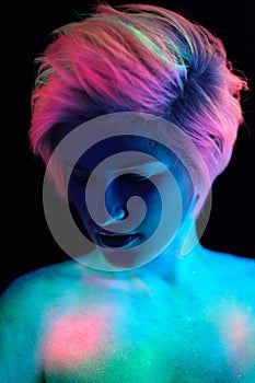 Model young beautiful girl portrait in studio with creative makeup, in neon ultraviolet lamp. Glows in the dark. Hair