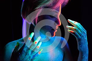 Model young beautiful girl portrait in studio with creative makeup, in neon ultraviolet lamp. Glows in the dark. Hair