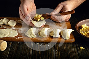 Modeling dumplings from dough and potatoes with your hands on the kitchen table for breakfast