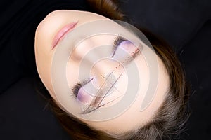 A modeling girl lies on the eyebrow modeling procedure with a marked architecture on her face