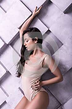 Beauteous alluring woman striking a pose near violet wall in studio photo