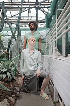 Models wearing extravagant clothing posing in greenhouse