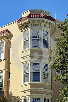 Moden spire or house tower with bay windows in midday sun with front yard trees and blue sky background with some shade