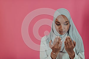 Modern African Muslim woman makes traditional prayer to God, keeps hands in praying gesture, wears traditional white