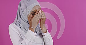 Modern African Muslim woman makes traditional prayer to God over colorful background