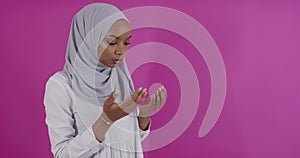 Modern African Muslim woman makes traditional prayer to God over colorful background