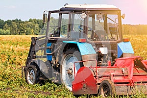 Modern agricultural tractor with harvesting equipment on an field